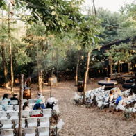 A serene outdoor event setting with white chairs, guests seated, and a stage area, evoking a calm, romantic atmosphere.