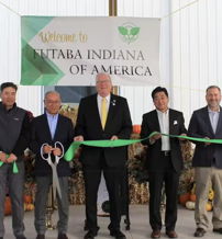 Ribbon-cutting ceremony with attendees celebrating new facility opening, conveying joy, teamwork, and anticipation.