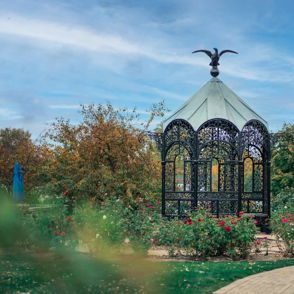 Elegant gazebo in a vibrant garden, surrounded by colorful flowers and a serene atmosphere, inviting for contemplation.
