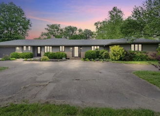 Modern single-story home amid lush greenery, featuring large windows, tranquil skies, and a welcoming atmosphere.