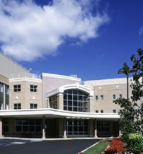 Modern hospital building with greenery, bright sky; evokes safety, hope, professionalism, and calmness in a healthcare setting.