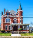 Victorian house with spire and brickwork, surrounded by a yard, under a clear sky, evoking nostalgia and charm.