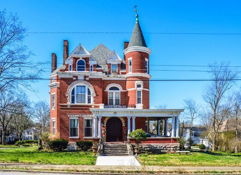Victorian house with spire and brickwork, surrounded by a yard, under a clear sky, evoking nostalgia and charm.