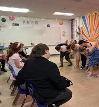 Students take a bow after a performance, conveying excitement and achievement in a vibrant classroom setting.