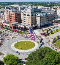 A vibrant aerial view of a bustling downtown with an American flag, showcasing community celebration and joy.