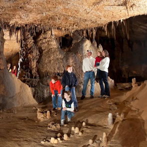 Group explores a cavernous space with impressive rock formations, evoking wonder and adventure in a vibrant, mysterious setting.