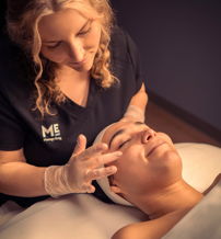A practitioner provides a soothing facial treatment to a relaxed client in a calm, inviting spa atmosphere.