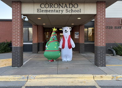 Festive scene at Coronado Elementary with a colorful Christmas tree and polar bear inflatables, celebrating holiday cheer.