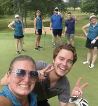 A cheerful group on a golf course takes selfies, evoking joy and camaraderie in a lively outdoor setting.