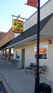 "Colorful sign of Velma's Good Cook Diner, inviting facade, outdoor seating, evoking nostalgia and community."