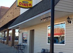 "Colorful sign of Velma's Good Cook Diner, inviting facade, outdoor seating, evoking nostalgia and community."