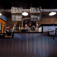 Modern café interior with staff at the counter, featuring industrial design, warm lighting, and a cozy, inviting atmosphere.