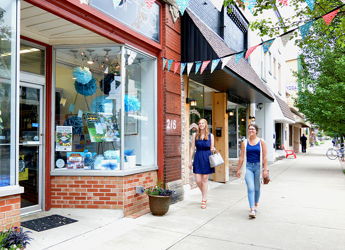 Lively street scene with women walking past colorful storefronts, conveying community, leisure, and a cheerful atmosphere.