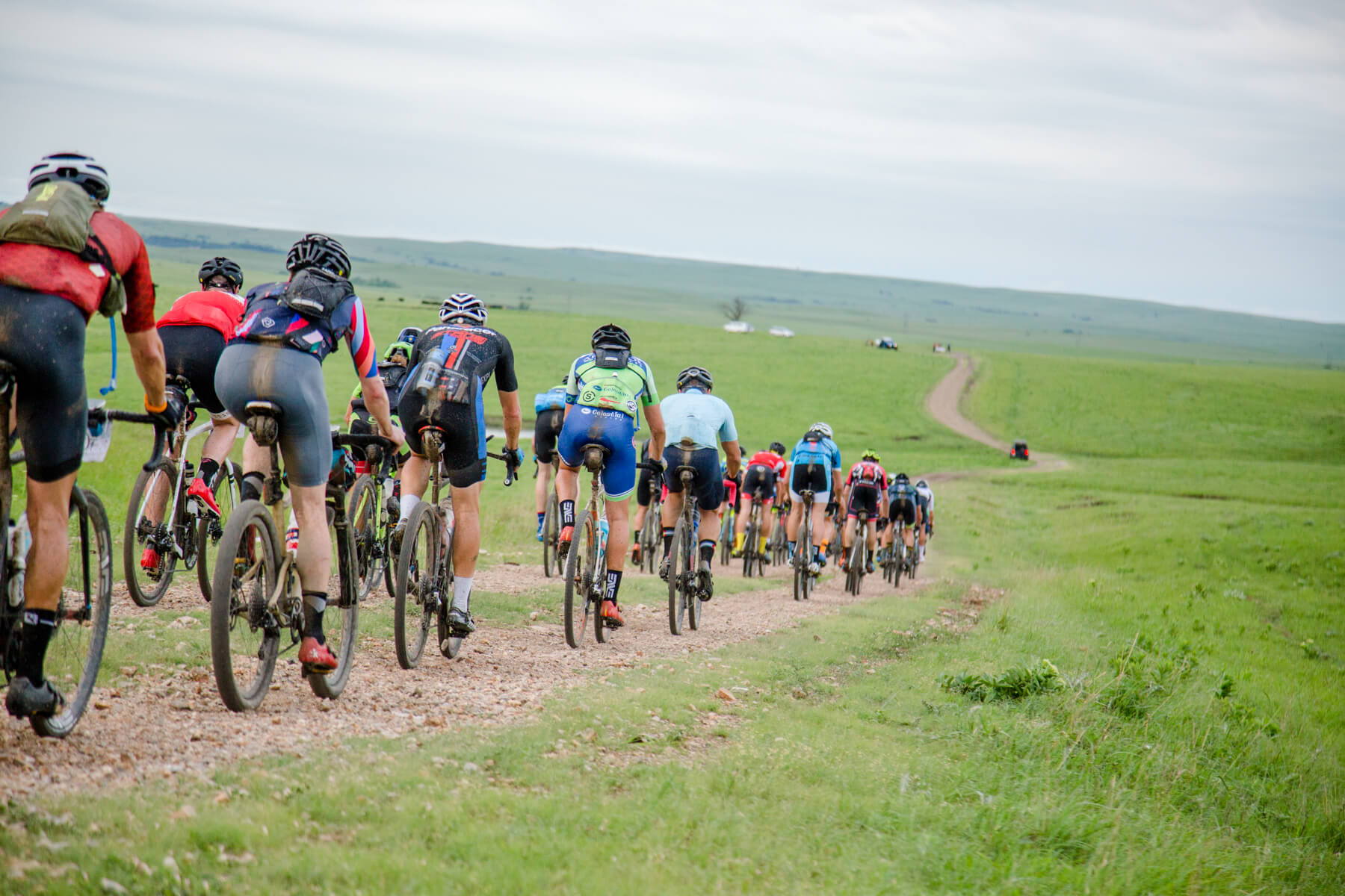 Cyclists ride on a gravel path through a lush landscape, evoking adventure, community, determination, freedom, and serenity.