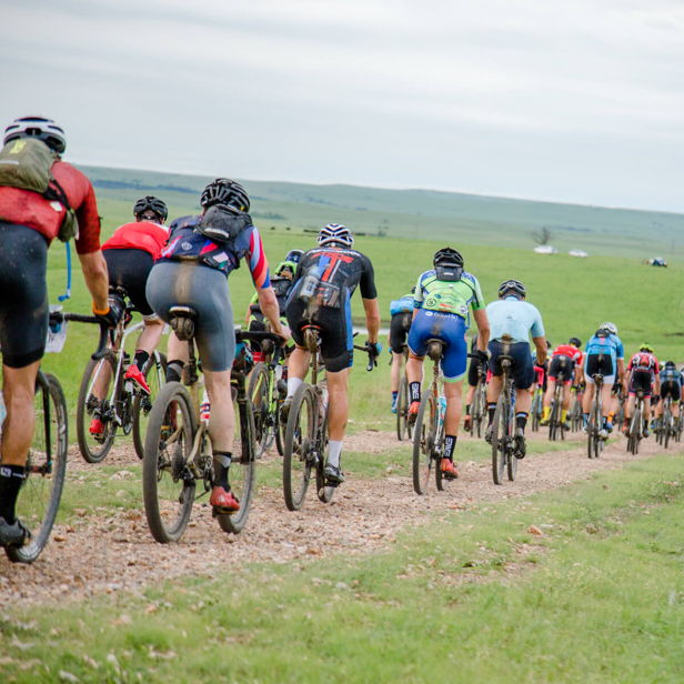 Cyclists ride on a gravel path through a lush landscape, evoking adventure, community, determination, freedom, and serenity.