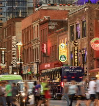 Vibrant city street scene at dusk with neon signs, bustling crowds, and a lively, festive atmosphere.