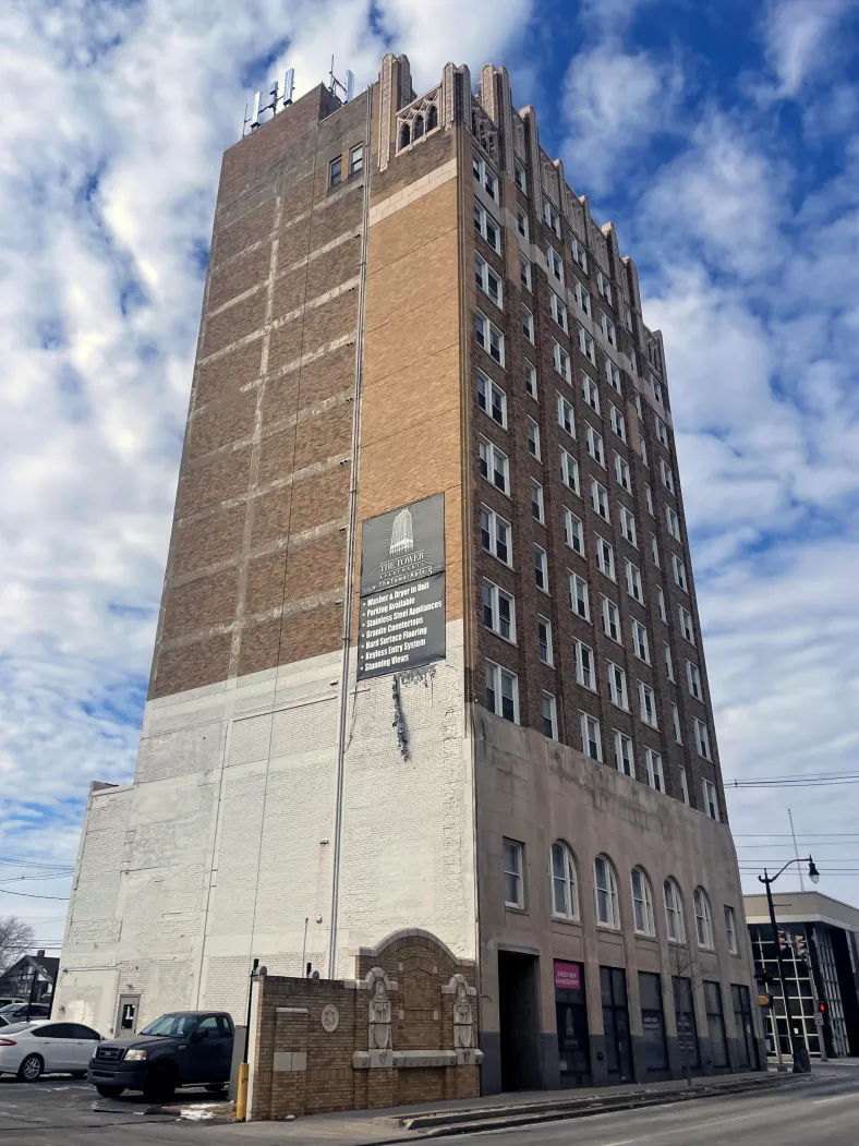 Tall, historic building of brick and plaster amidst partly cloudy skies, evoking nostalgia and contemplation of urban life.