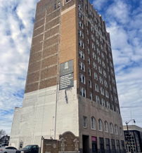 Tall, historic building of brick and plaster amidst partly cloudy skies, evoking nostalgia and contemplation of urban life.