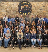 A diverse group poses warmly for a photo at the "1861 CLUB," showcasing camaraderie and celebration in casual to semi-formal attire.