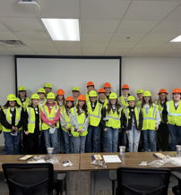 Group of people in bright yellow vests and colorful hard hats in a professional setting, conveying teamwork and safety.