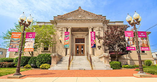 Historic building with columns and stairs, surrounded by greenery and banners, evokes community and joy on a bright day.