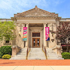 Historic building with columns and stairs, surrounded by greenery and banners, evokes community and joy on a bright day.