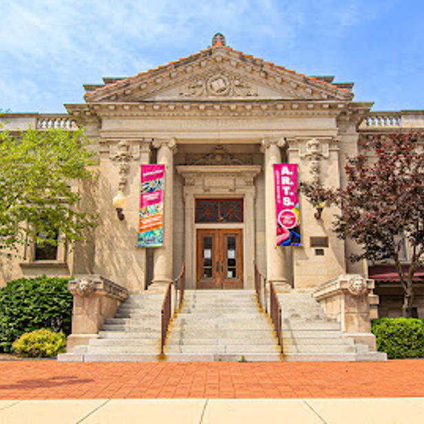 Historic building with columns and stairs, surrounded by greenery and banners, evokes community and joy on a bright day.
