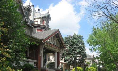 Charming house with gabled roof, lush landscape, bright sky, evoking tranquility and nostalgia in a peaceful neighborhood.