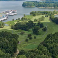 Scenic view of water surrounded by greenery, golf course, and marina, evoking tranquility and inviting outdoor leisure.