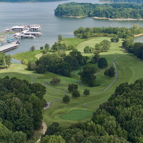 Scenic view of water surrounded by greenery, golf course, and marina, evoking tranquility and inviting outdoor leisure.
