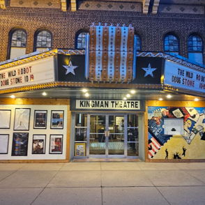 Vintage theater interior with maroon seats, balcony, warm lighting, and elegant decor, evoking nostalgia and excitement.
