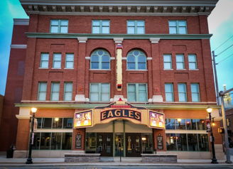 Elegant theater with plush seating and a stage draped in red curtains, evoking excitement and anticipation for performances.