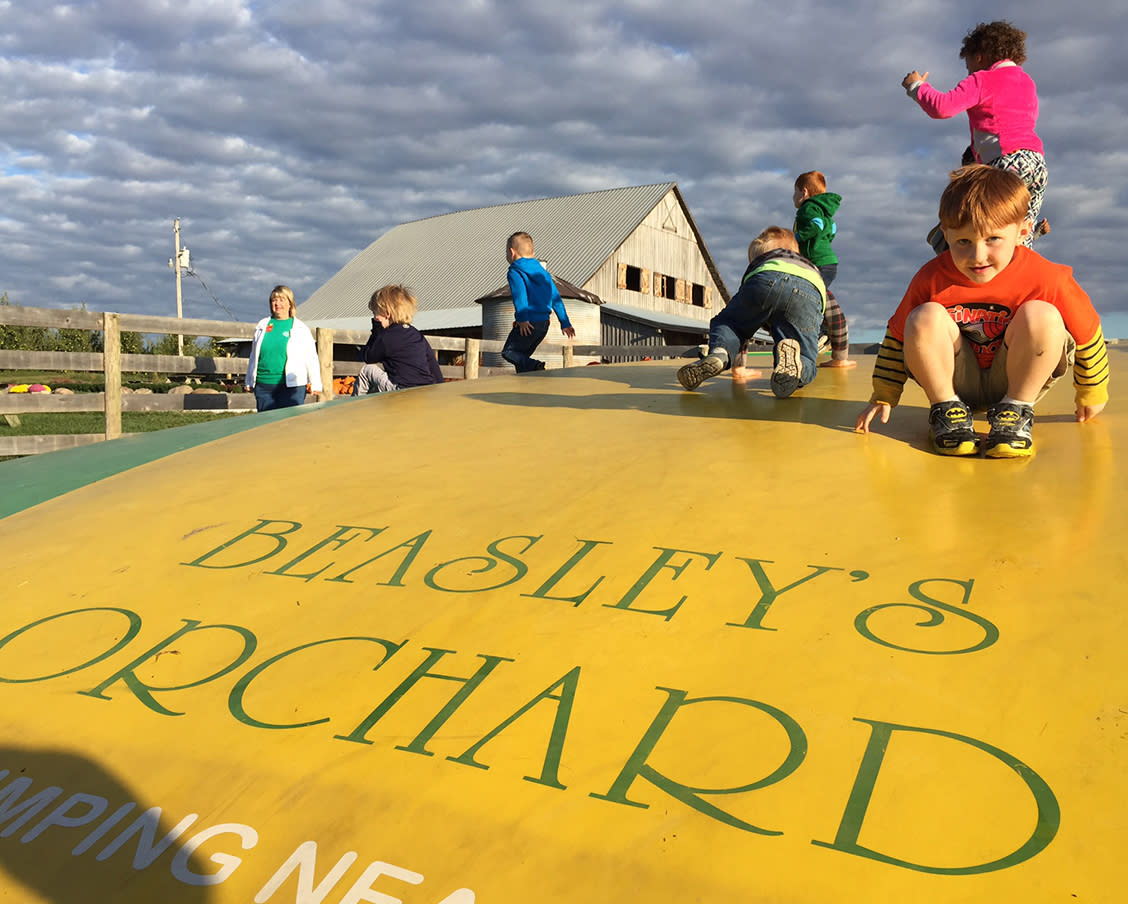 Children play joyfully on a large yellow inflatable at Beasley's Orchard, capturing the carefree spirit of childhood.