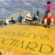 Children play joyfully on a large yellow inflatable at Beasley's Orchard, capturing the carefree spirit of childhood.
