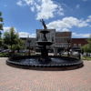 A sunny urban fountain surrounded by greenery and buildings evokes tranquility and joy, perfect for community gatherings.