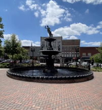 A sunny urban fountain surrounded by greenery and buildings evokes tranquility and joy, perfect for community gatherings.