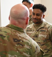 Two military personnel in camouflage engage in conversation, showcasing camaraderie and teamwork in a professional setting.