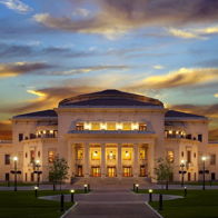 Grand theater with classical design at sunset, highlighted by warm colors and elegant surroundings, evoking grandeur and inspiration.