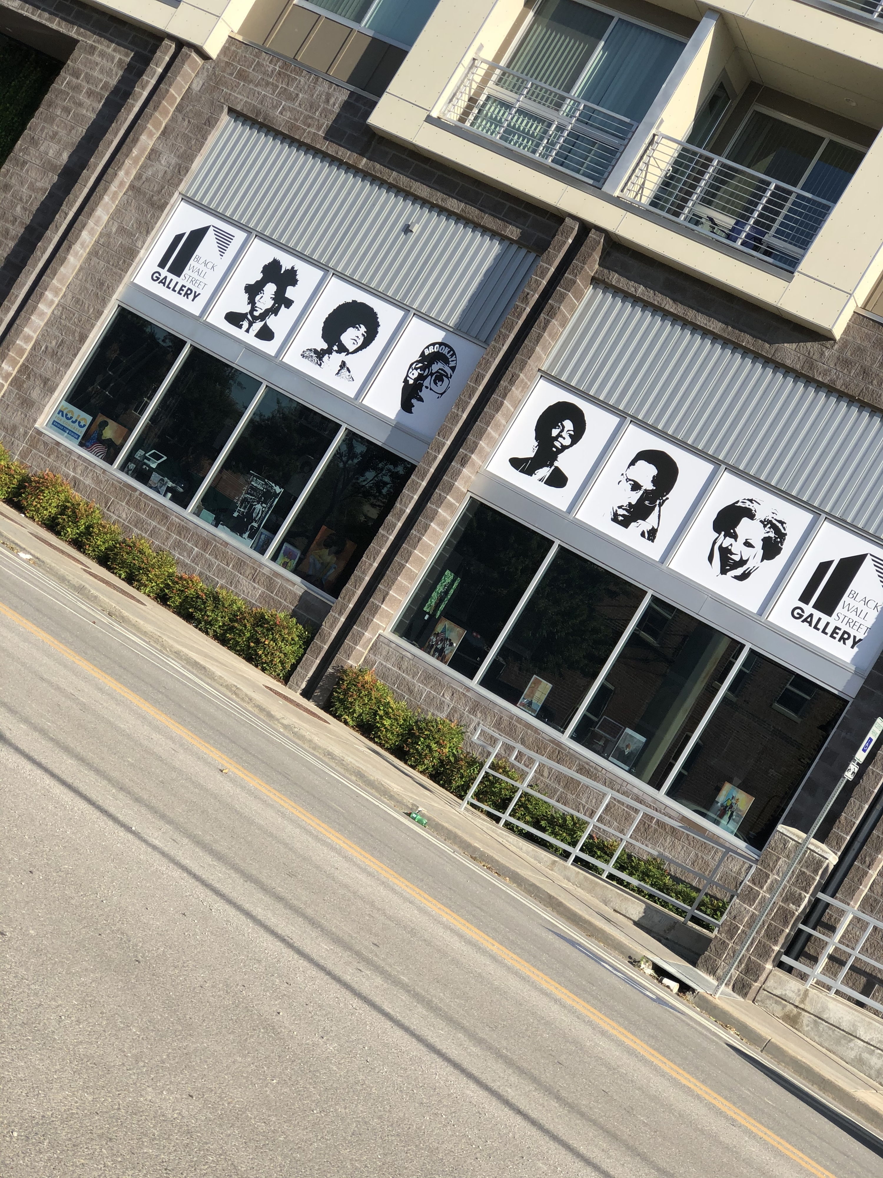 Modern building facade with large grid windows displaying striking black and white graphic images, evoking creativity and community.